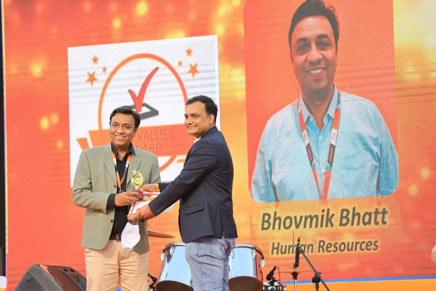 Balloon arch in orange, black, and white colors framing an ITT logo board lit with warm lights